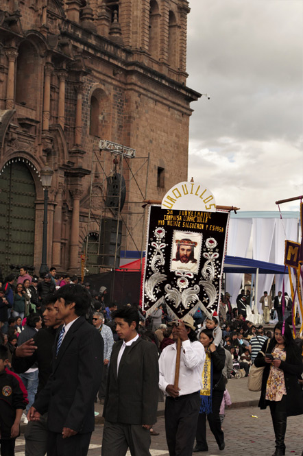 A marching group sign that reads "Urquillos - Sr Torrechayoc Comparsa Ccapac Dolla Myo Vicente Salgueron Y Esposa"